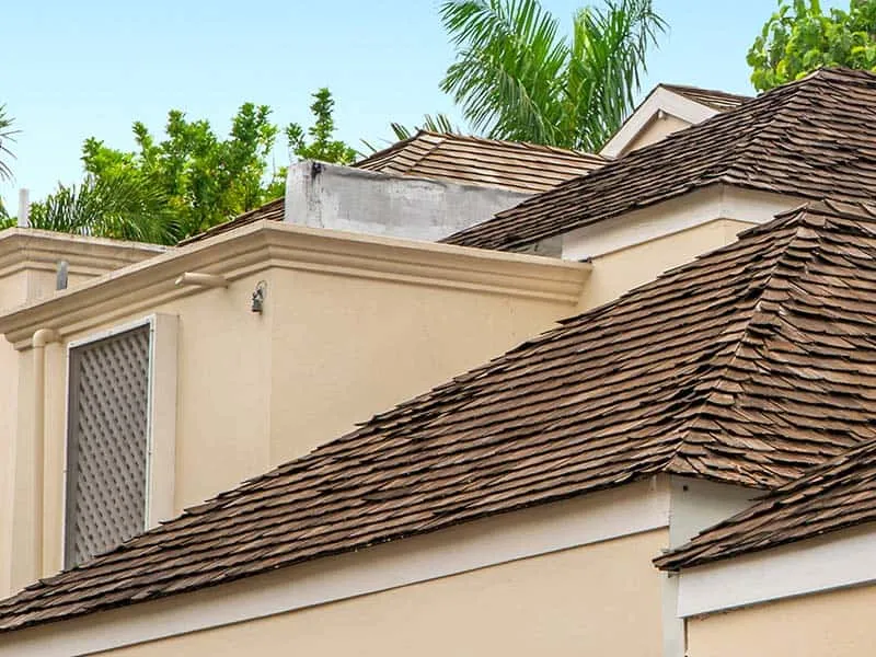 Deteriorating cedar shake roof showing rot splitting and moss damage on a Florida home